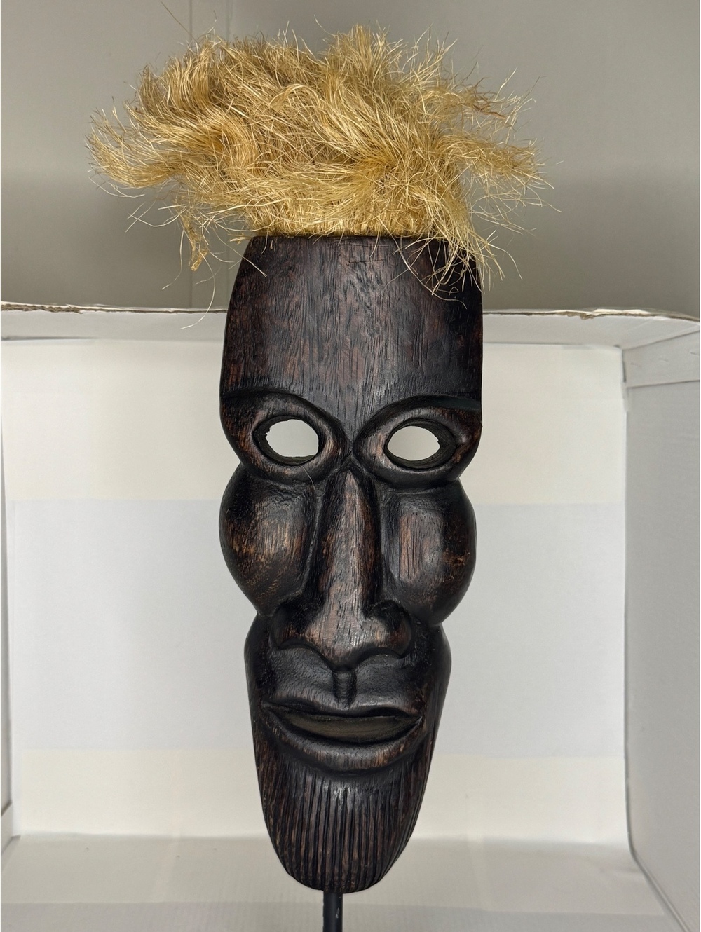 Wood mask on stand with raffia hair